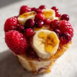 Handmade candy cup of banana split, raspberries, cranberries, decorated with honey